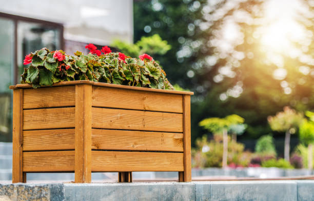 Decorative Wooden Planter Box with Blooming Red Flowers Arranged in the Residential Backyard Garden. Landscaping Design Ideas.