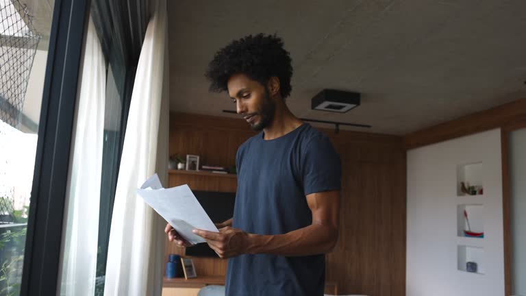 Black man at home analyzing some documents looking very happy