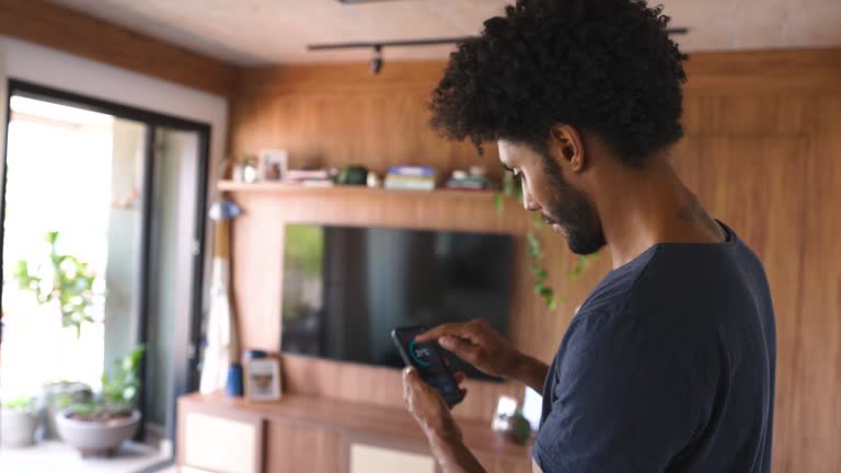 Brazilian man adjusting the temperature of his house using a mobile app on his cell phone