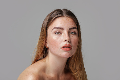 Studio beauty portrait of very natural woman with freckles on her face. Girl looking at the camera. A lot of copy space. Skin care concept. Ideal, delicate makeup.