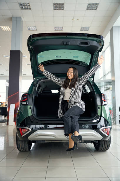 Beautiful asian woman rejoices in a new car Beautiful asian woman rejoices in a new car, car trunk is open happy car asian stock pictures, royalty-free photos & images