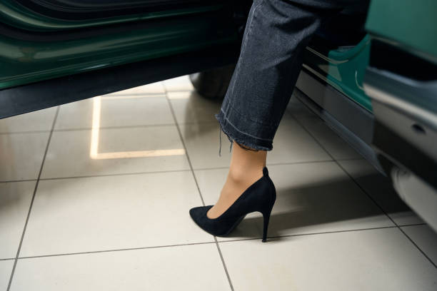 Shopper opens the door of a modern car and puts her foot on the floor, a woman in stylish stilettos