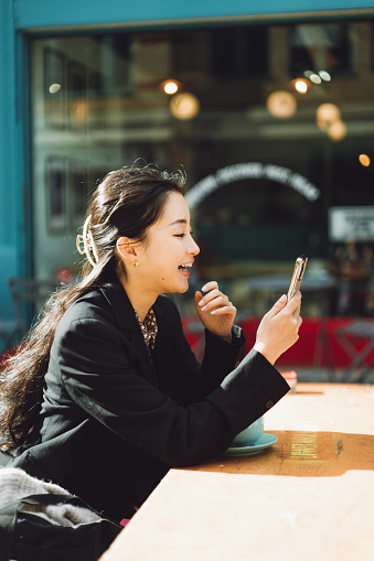 Beautiful Asian businesswoman working in a cafe with her smartphone