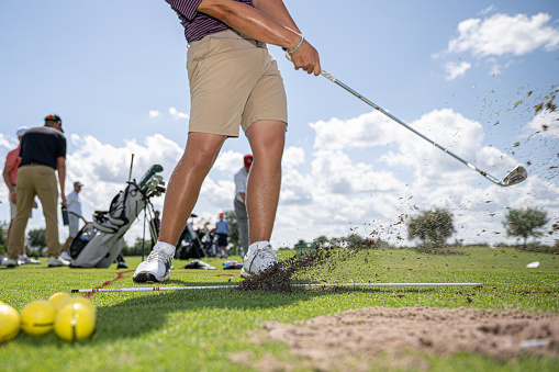 The picture depicts a golf green with a smooth, well-manicured surface. The grass is a lush shade of green, and there are several small holes scattered across the surface. The focal point of the image is a collection of bright yellow golf balls, which are scattered throughout the green. The balls are arranged in a seemingly random pattern, with some clustered together in small groups and others spread out on their own. The overall effect is one of precision and attention to detail, with the yellow balls providing a striking contrast against the green backdrop