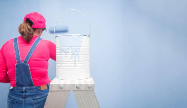 white paint can with blue paint dripping on a metal ladder