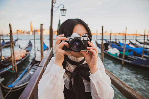 An Asian tourist in Venice takes a photo with her reflex camera