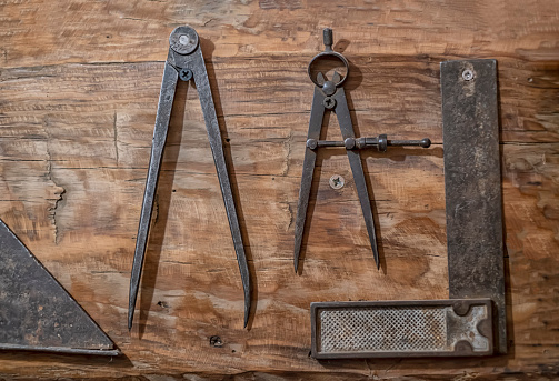 antique tools of carpenter on a wood, antique compass to trace and a square for wood edging, old drawing equipment, horizontal