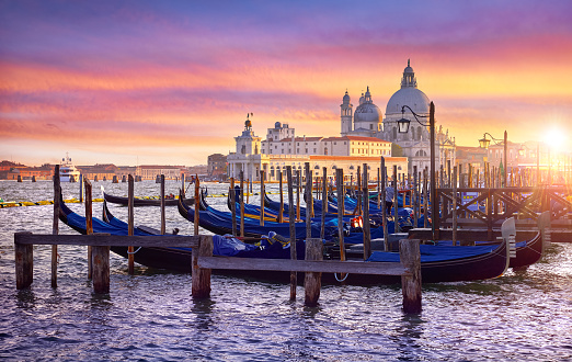 Venice Italy. Gondolas floqting by the docks of Grand Canal in Venezia. Sunset view Cathedral Santa Maria della Salute Picturesque panoramic skyline landscape