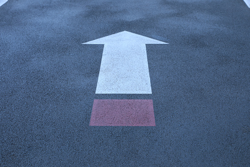 White and red direct arrow on asphalt street. Direction indicator. Signs on the street.