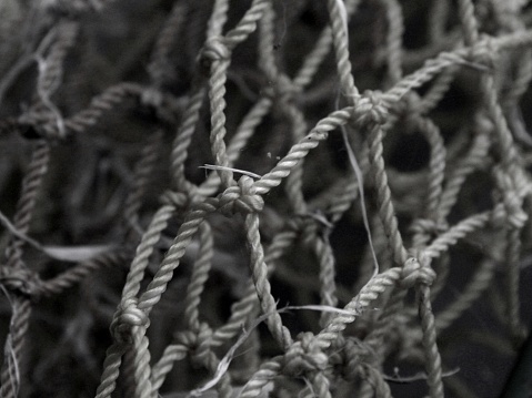 A black and white photograph of a section of a shabby net used to catch fish