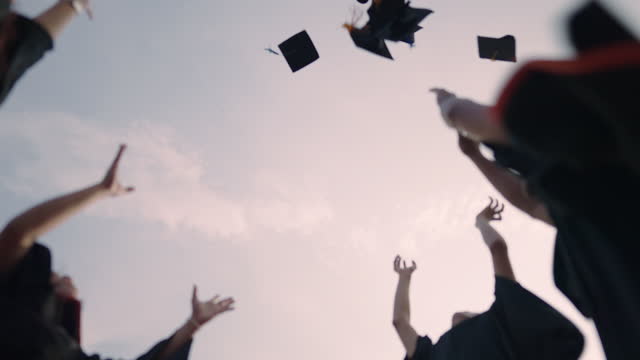 Close-up of Students throwing in the Air Blue sky graduation hats in the air celebrating