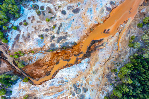 Dried rusty river bed over wasteland grey background, contamination texture, drone view directly above from drone