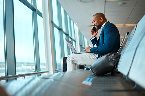 Phone call, travel and businessman on a laptop in the airport for work company trip in the city. Technology, communication and African male employee on mobile conversation waiting to board his flight