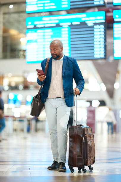 istock Black man with phone, luggage and checking flight schedule online, waiting in terminal for international business trip. Internet, travel app and businessman at airport for international destination. 1485259995
