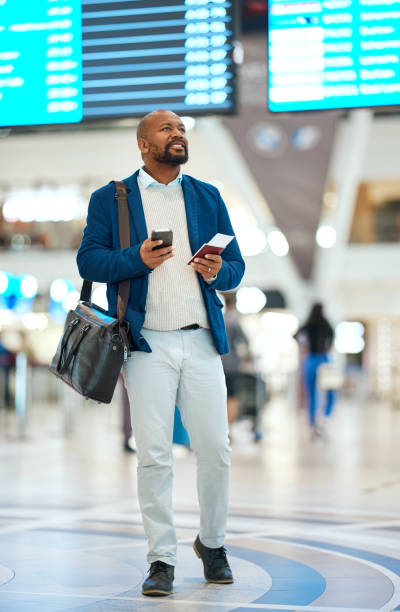 istock Black man checking flight schedule with phone and ticket walking in airport terminal, holding passport for business trip. Smile, travel app and happy businessman boarding international destination. 1485259998