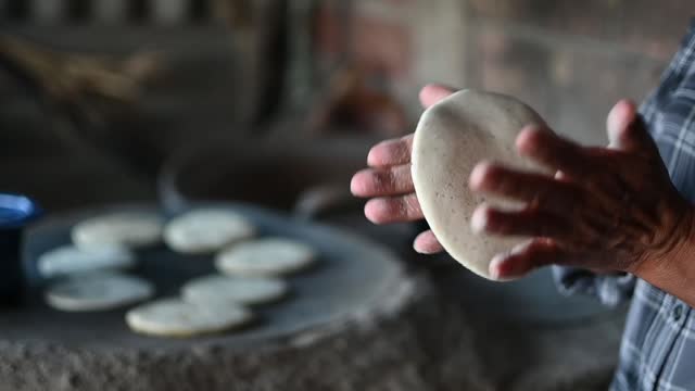Mexican woman making a corn tortillas in a traditional way