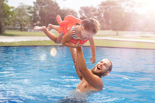 Dad holding child in his arms in the pool