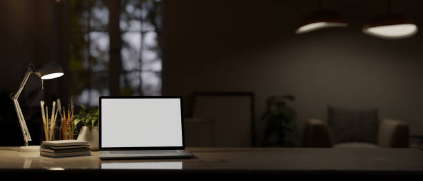 istock Dark modern office room at night time with blank screen laptop computer on the table 1485270684