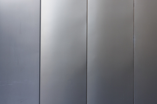 Close-up on an a grey metal wall divided in four parts.