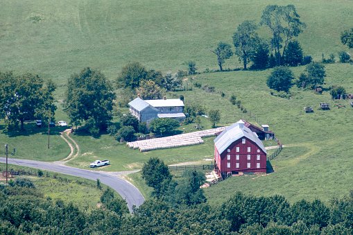 Zoomed into a farm at the bottom of a valley from a scenic overlook. farm is dilapidated and Appears to be working on the ragged edge of survival. Hard working folks doing the best they can.