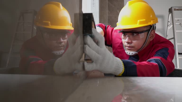 Asian young worker wearing safety gear is using a water level to accurately measure cement building construction. Construction Inspection concept