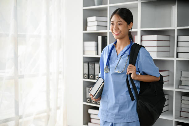 Young Asian medical student smiling and standing in the study room.