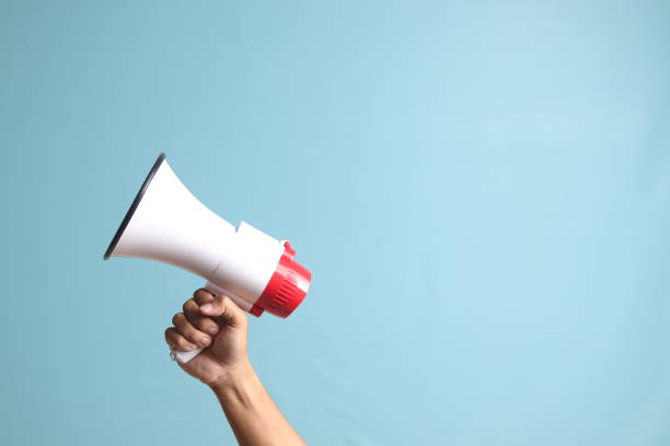istock male hand holding megaphone, announcing advertisement. Isolated image on blue background 1485295102