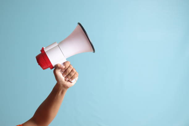 istock male hand holding megaphone, announcing advertisement. Isolated image on blue background 1485295132