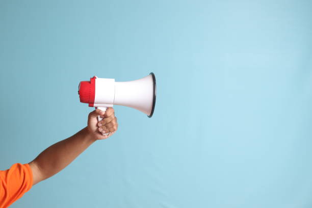 istock male hand holding megaphone, announcing advertisement. Isolated image on blue background 1485295133