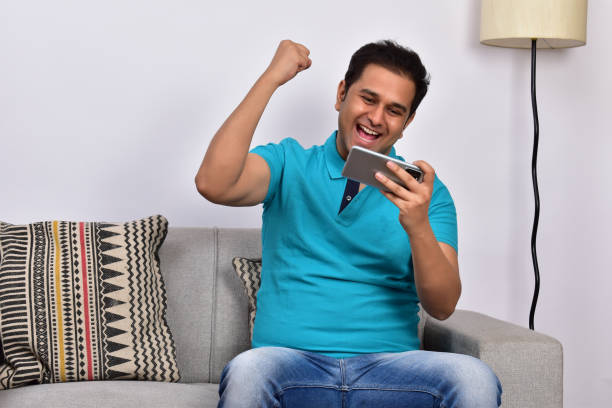 istock Young adult man at home sitting on sofa using smartphone 1485301988
