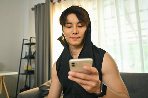 istock Young sportsman using smartphone on couch, resting after morning workouts at home. 1485307568