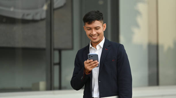 istock Millennial businessman using smartphone while sitting outside office building. Modern lifestyle and technology concept. 1485307673