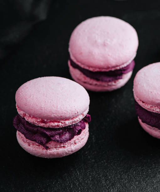 istock Pink macarons with chocolate filling on black stone 1485308350