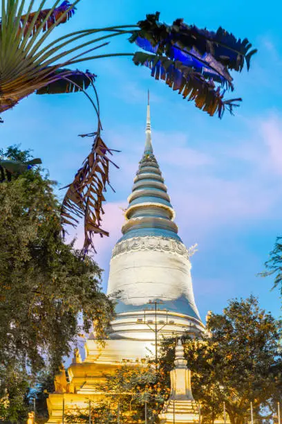 In Wat Penh gardens,a gift from China,covered in green grass,a large working clock,beneath the hilltop pagoda of Wat Phnom,a prominent city landmark,next to the circular pathway.