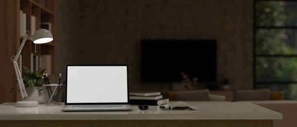 istock Home workspace at night time with laptop mockup, table lamp, and stationery on a table 1485311532