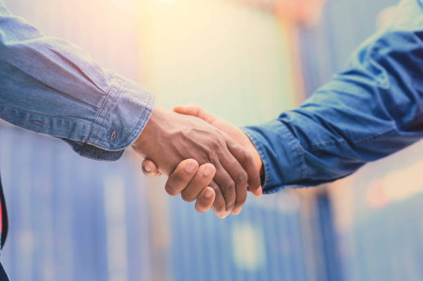 istock Close up to African African american engineer handshake together at container cargo yard in successful. success in logistics business import export industry. 1485312648