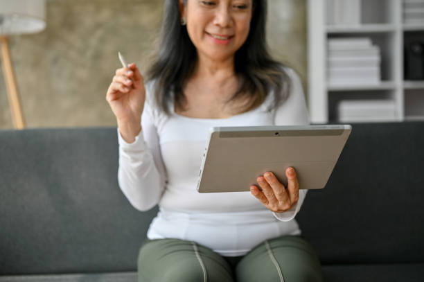 istock Senior woman using tablet while sitting on the sofa at home. 1485314374