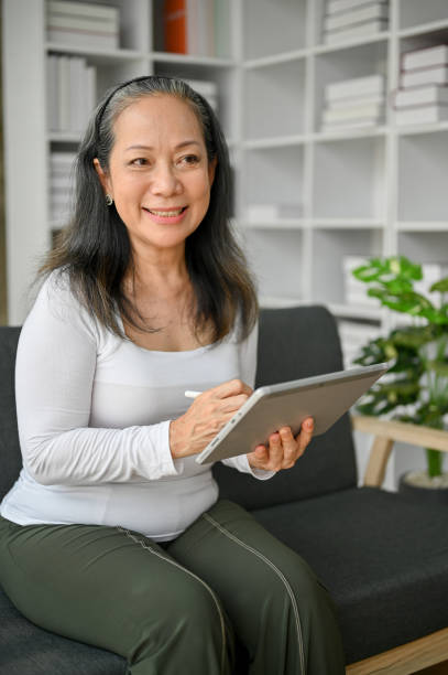 istock Senior woman using tablet while sitting on the sofa at home. 1485314384