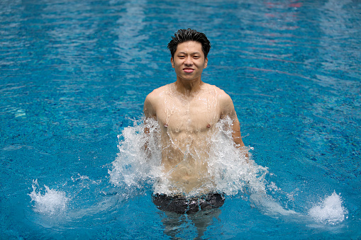 An Asian young adult is relaxing in the swimming pool