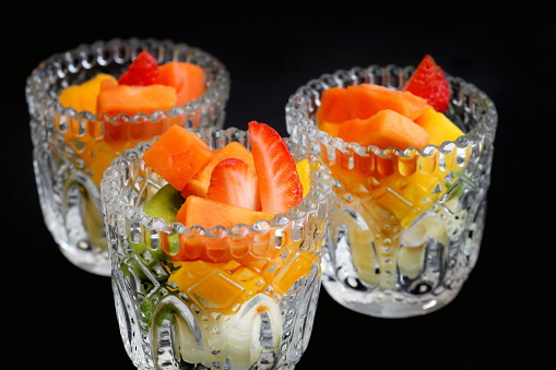 fruit salad in glass cup on black background