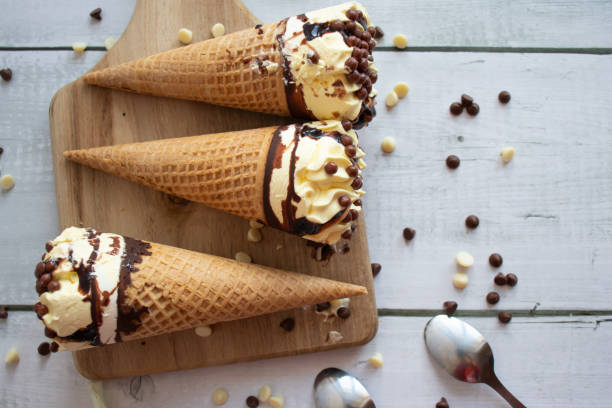 istock Vanilla chocolate ice cream cone. On a white wooden background. Sweets 1485321159