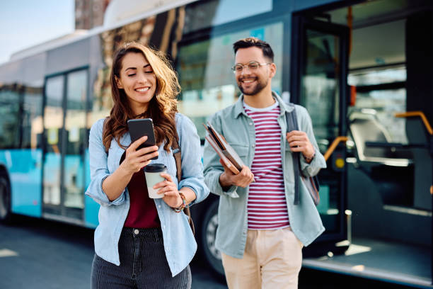 istock Happy couple using mobile phone while getting of a bus at the station. 1485324074