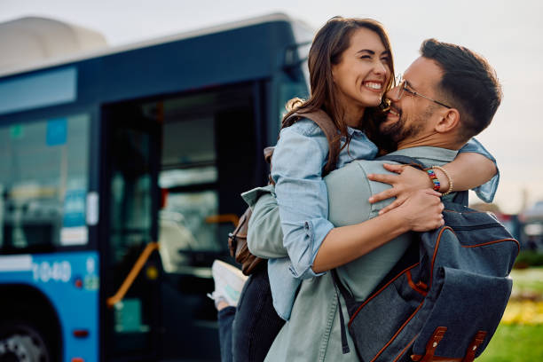 Young cheerful couple embracing at bus station.