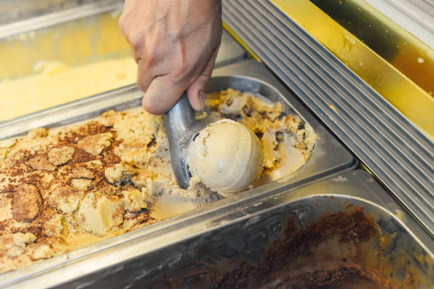 mão colhendo uma colher de sorvete em uma colher na geladeira - soft serve ice cream - fotografias e filmes do acervo