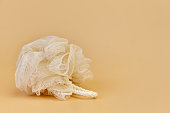 Beige mesh pouf bath sponge washcloth, single object on beige background