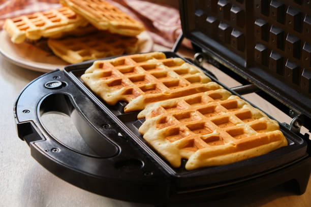 istock waffles are baked waffle iron machine. Belgian waffle dessert. 1485333921