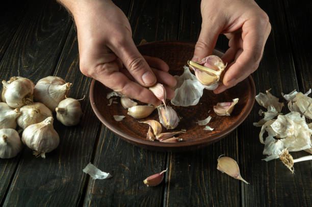 istock The chef cleans the garlic in a vintage plate on the kitchen table before preparing a vegetarian meal. Tasty recipe concept on black background 1485334805