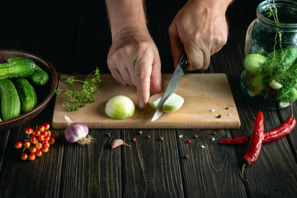 enlatamento de pepinos em um pote com cebola e especiarias. close-up das mãos do cozinheiro com uma faca cortada cebola - jar canning food preserves - fotografias e filmes do acervo