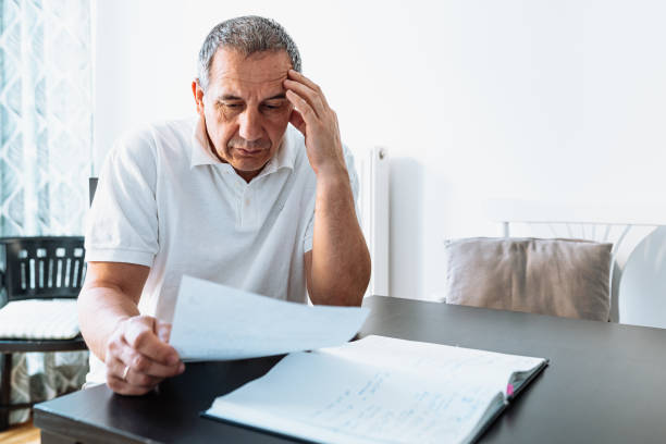 istock middle-aged man at table at home reading bill or letter 1485338901