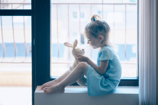 istock Cute little girl sitting on windowsill 1485339111